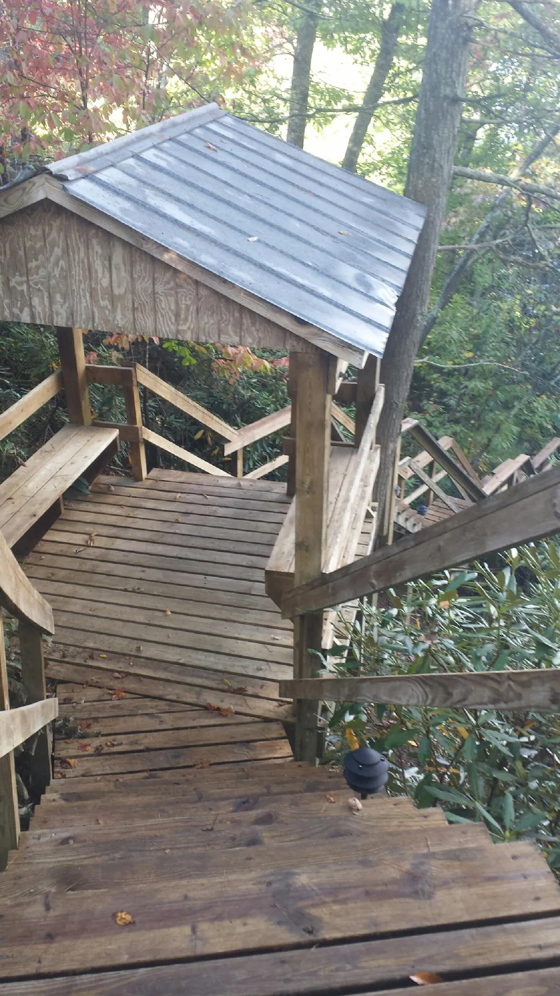 Metal roofed shelter over wooden steps on a wooded walkway — Skylight Repair & Installation work by our crew in Weston